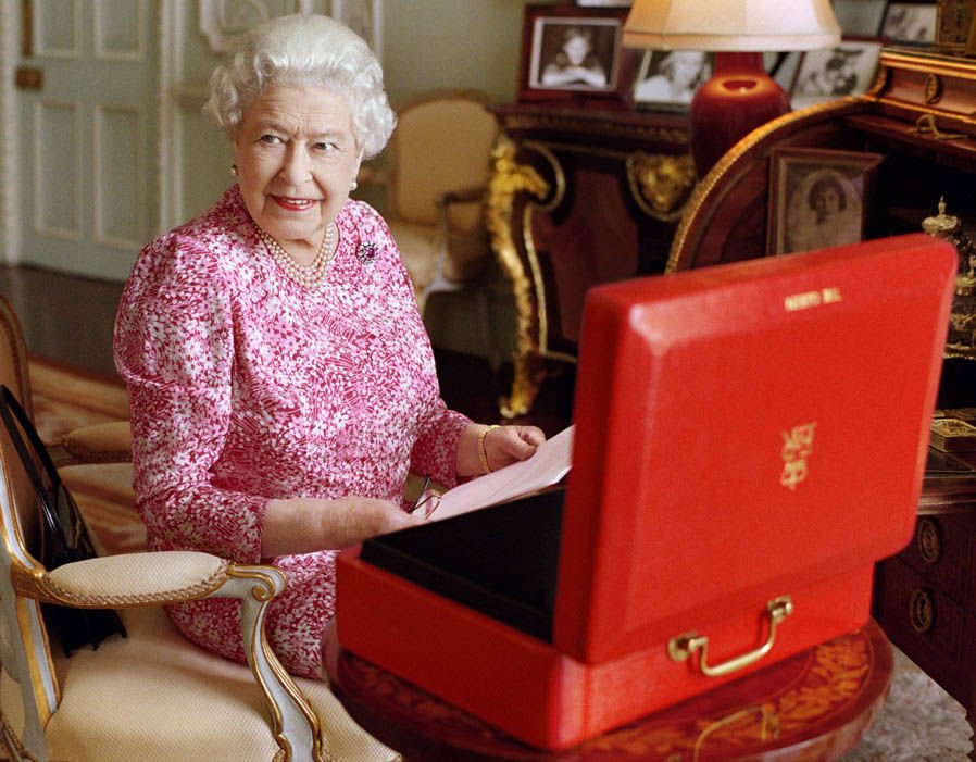 The Queen sits at her desk with her red box of official government papers. Mary McCartney